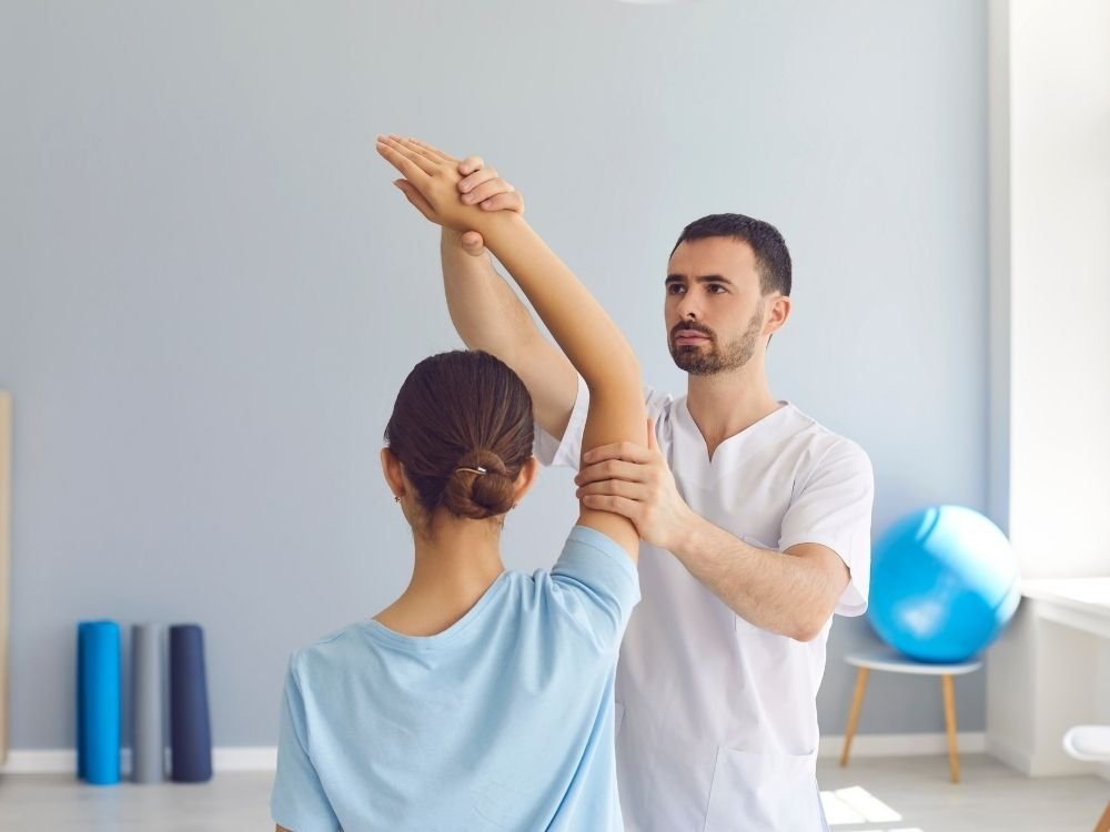 Illustrative physiotherapist guiding a seated patient through a leg movement