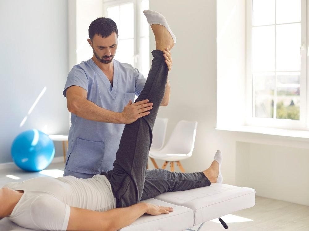 Illustrative physiotherapist supervising a patient performing a supported exercise on a mat